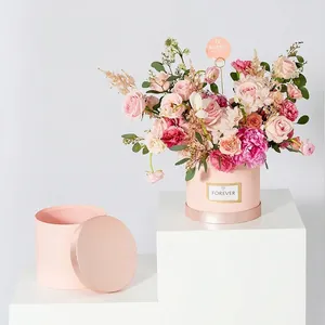 Elegante caja de regalo redonda rosa para flores con borde brillante y etiqueta dorada