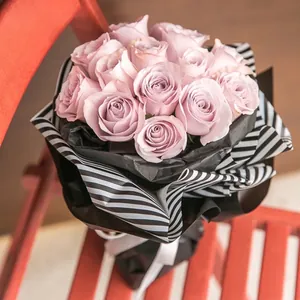 Elegante bouquet di rose lavanda avvolto in carta regalo a righe bianche e nere