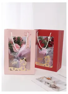 Elegant pink and red gift bags with transparent windows holding fresh carnation bouquets