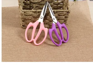 Detailed view of pink and purple florist scissors leaning against a woven basket