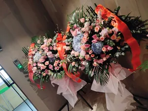 Vibrant red opening ceremony banners with gold borders displayed on large floral baskets