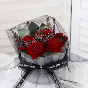 Elegant rose gold bridal crown with black gems on a bouquet of red roses for gifting.