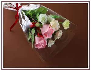 Gros plan de cellophane OPP transparente enveloppant un bouquet de roses avec ruban rouge