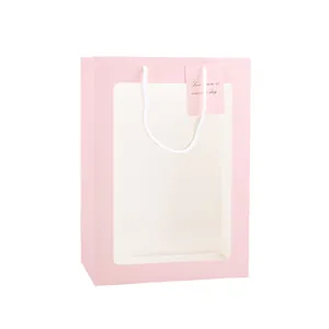 Elegante roze papieren cadeautas met een transparant venster en witte koordhandvatten.