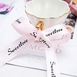 Elegant roze satijnen lint met Sweetlove print, geknoopt als strik voor cadeauverpakking