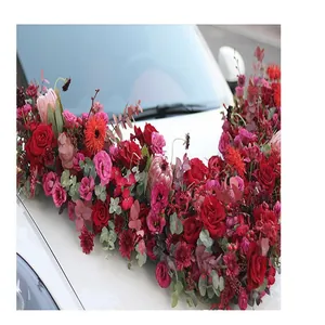 Elegant rood en roze bloemstuk op de motorkap van een witte trouwauto detail decoratie