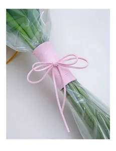 Close-up detail of pink faux suede cord tied in a bow for flower bouquet wrapping.