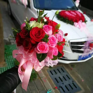 Detailed macro view of a bridal hand bouquet featuring fresh red and pink roses with lace trim
