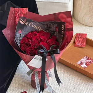 Elegante ramo de rosas rojas envuelto en papel de floristería rojo y negro texturizado