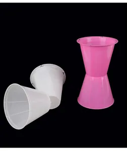 Detalle de soportes de conos de plástico para arreglos florales en rosa y blanco sobre fondo negro