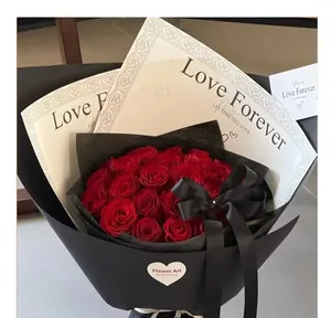 Vista detallada de un ramo de rosas rojas envuelto en encaje elegante y papel negro mate