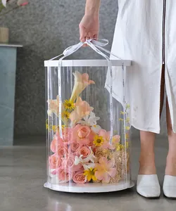 Detailed view of an elegant clear round PVC flower box held by a model with branded ribbon