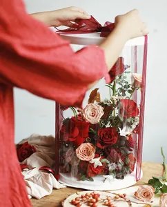 Transparent round PVC flower box with red ribbon bow for elegant floral arrangements.