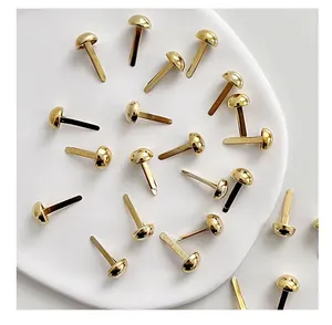 Detailed macro view of shiny gold round head brads organized on a white ceramic display plate.