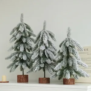 Three snowy artificial Christmas trees with natural wooden bases for festive decor