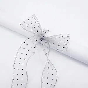 Translucent white sheer chiffon ribbon with black polka dots tied in a decorative bow