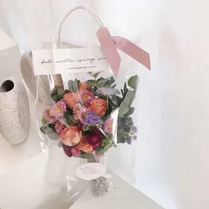 Detalle de una bolsa de regalo de PVC transparente para flores con asas y lazo rosa