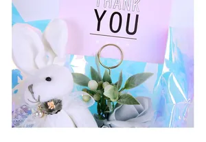 Nahaufnahme eines goldenen Kartenhalters in einem Geschenkstrauß mit einem Plüschhasen-Zubehör.