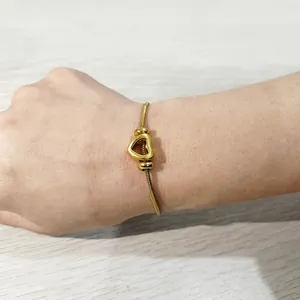 Bracciale con ciondolo a cuore d'oro al polso con catena a serpente in acciaio 18k.