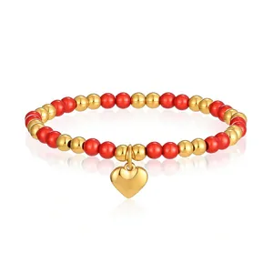Primo piano del bracciale elastico con perline rosse e oro e ciondolo a cuore in acciaio