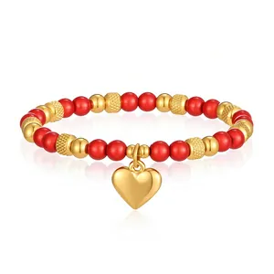 Vista dettagliata di un bracciale a perle rosse con ciondolo a cuore in acciaio dorato.