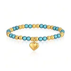 Primo piano del bracciale di perle in acciaio inossidabile con ciondolo a cuore oro e perle teal
