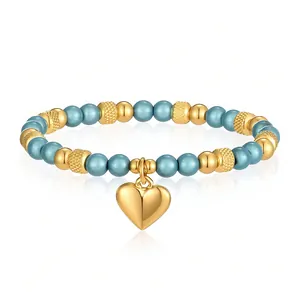 Dettaglio di un bracciale elastico con perle blu e un ciondolo a cuore in oro lucido.