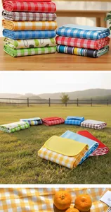 Detailed view of various folded colorful plaid and patterned waterproof picnic mats on grass.