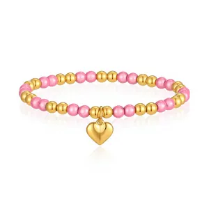 Primo piano del bracciale di perle rosa e dorate con un lucido ciondolo a forma di cuore.