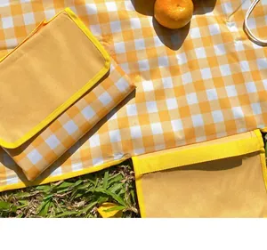 Detailed view of a yellow and white checkered waterproof picnic mat on lush green grass
