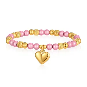 Vista dettagliata delle perle rosa scintillanti e del ciondolo a cuore dorato sul bracciale