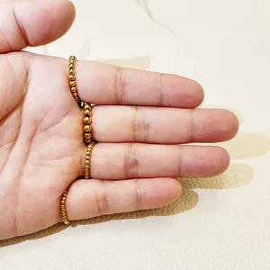 Detalle de un anillo elástico de cuentas de acero inoxidable chapado en oro en los dedos