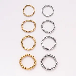 Detalle de anillos elásticos de cuentas de acero titanio en dorado y plateado, varios tamaños.