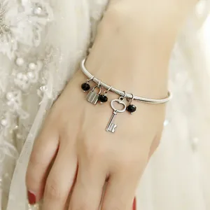 Detail of a vintage stainless steel snake chain bracelet with lock and key charms.