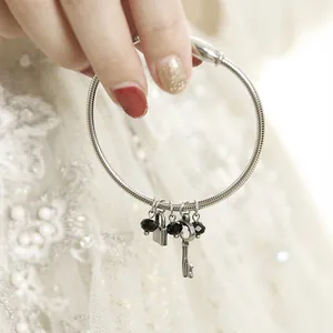 Macro detail of vintage lock and key charms on a silver stainless steel spring bracelet