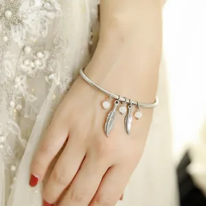 Detail view of a vintage stainless steel bracelet with feather charms and beads