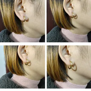 Vue détaillée de plusieurs boucles d'oreilles créoles minimalistes en titane doré sur l'oreille.