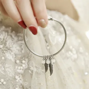 Detail view of 304 stainless steel bracelet featuring delicate feather charms and beads
