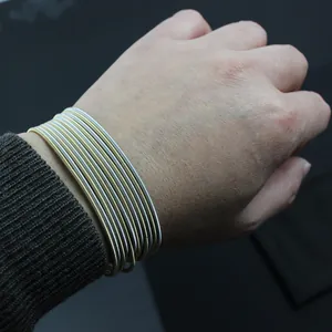 Close-up of 1.7mm 304 stainless steel gold and silver spring coil bracelets on wrist.