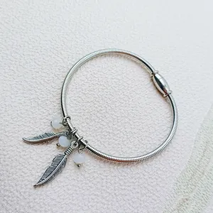 Detailed view of stainless steel spring bracelet with feather charms and magnetic clasp