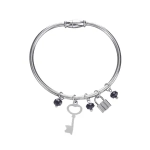 Detail view of a stainless steel bracelet featuring a heart-shaped key and lock charms