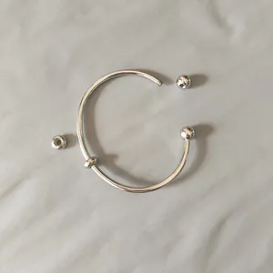 Detailed view of stainless steel open bangle with detachable screw-on ball ends