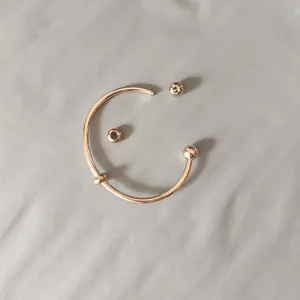 Close-up view of a rose gold titanium steel bangle featuring a screw-off ball end.