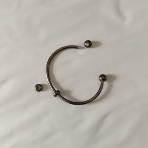 Close-up of gun-metal stainless steel open cuff bracelet with screw-on ball ends