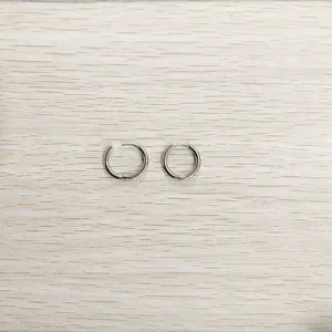 Vue détaillée de boucles d'oreilles créoles en acier titane argenté sur bois