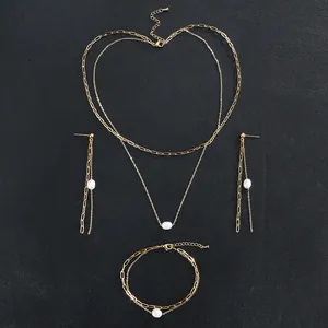 Detail view of gold stainless steel jewelry set with white freshwater pearls and delicate chains.