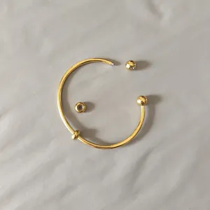 Close-up of golden stainless steel open bangle with screw-on detachable ball ends