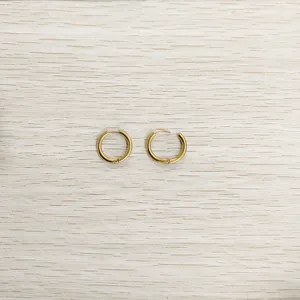 Vue détaillée de boucles d'oreilles créoles dorées en acier titane avec fermoir sécurisé.