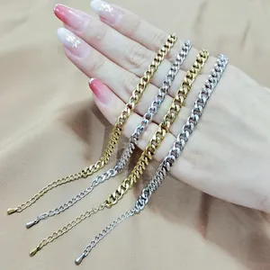 Primo piano di bracciali a maglia cubana in acciaio inox oro e argento su una mano