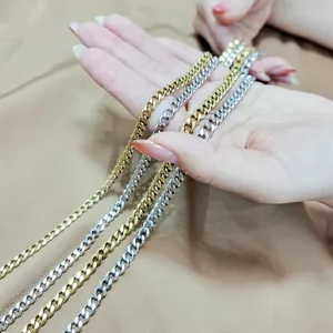 Gros plan de colliers à mailles cubaines en acier inoxydable or et argent à la main